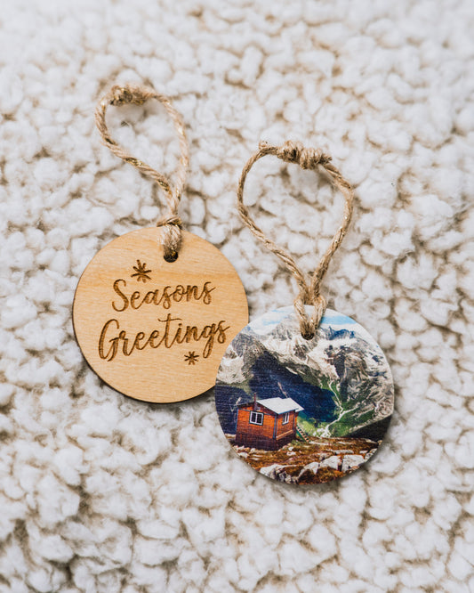 Adorno navideño circular de madera<br> Felices Fiestas<br> Cabaña en las Montañas